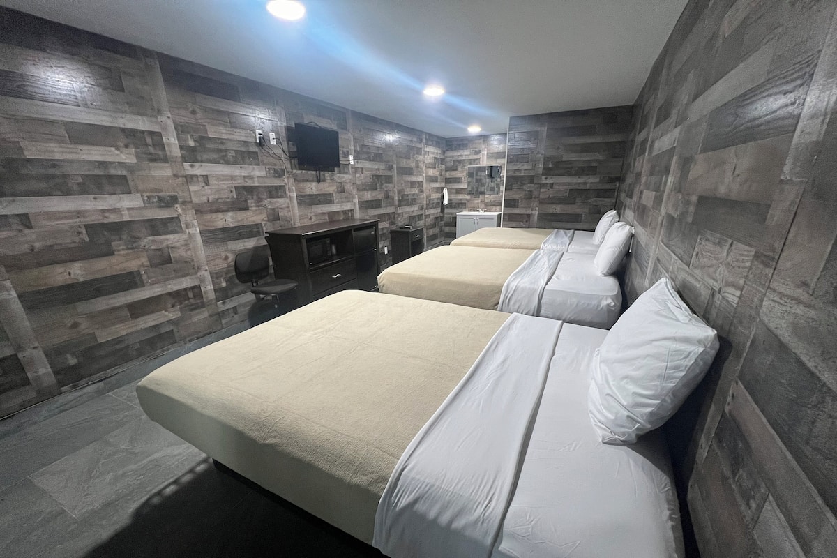 A modern hotel room with two beds, a desk, and a TV mounted on the wall.