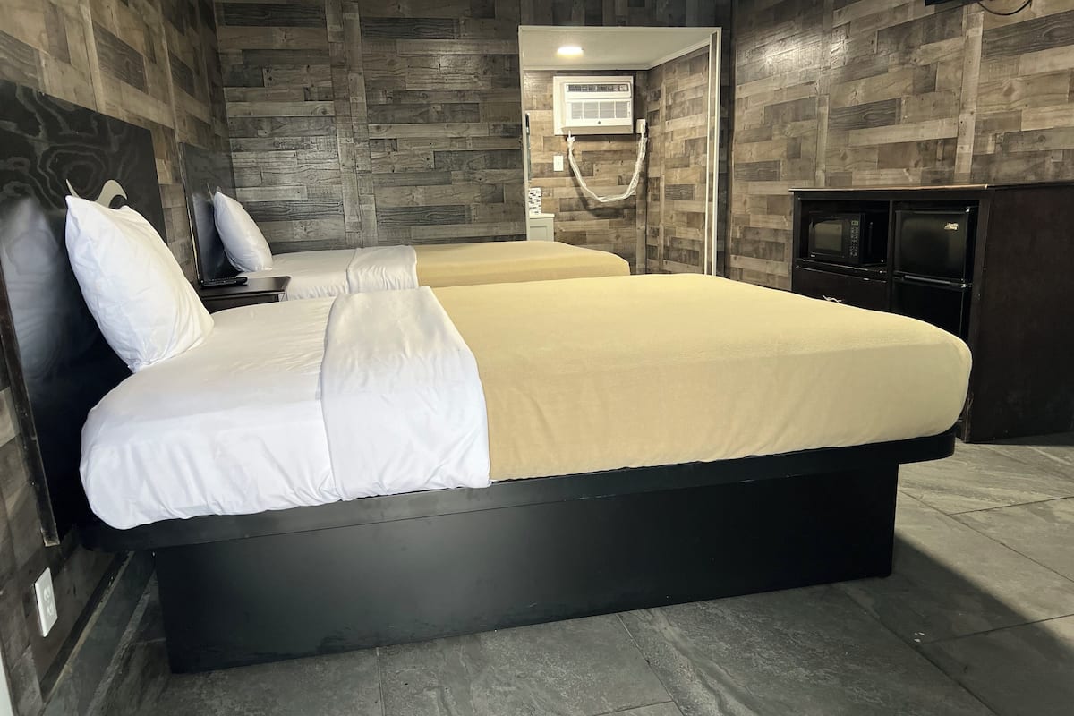 A modern hotel room with a large bed, a TV, and a built-in air conditioning unit.