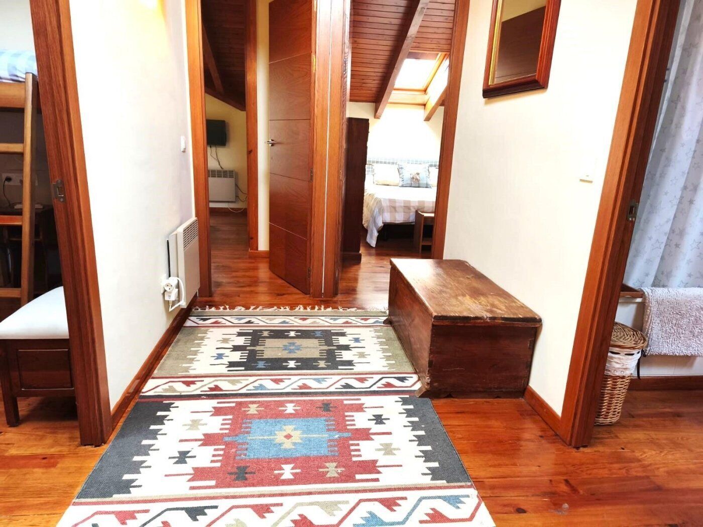 A hallway with wooden flooring, a bench, and a patterned rug.