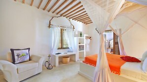 A bedroom with a canopy bed, a sofa, a small desk, and a hanging chair. - THE PALMS VILLA - Six Bedroom Villa, Sleeps 12 (South East Zanzibar)