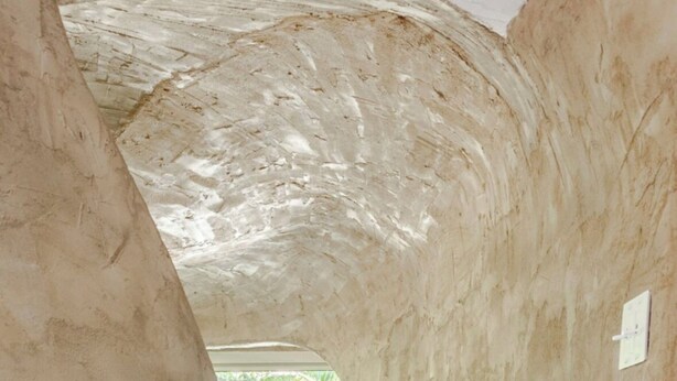 A narrow, curved hallway with a wooden floor and a window at the end.