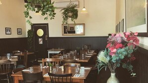 A restaurant interior with wooden tables and chairs, hanging plants, and framed pictures on the walls. - The Pinnacle Carlton 69th Floor City Views (Carlton)