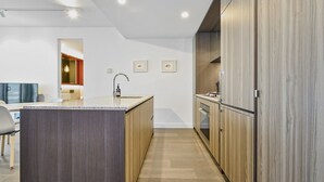 A modern kitchen with wooden cabinets, a central island, and a built-in oven. - The Pinnacle Carlton 69th Floor City Views (Carlton)