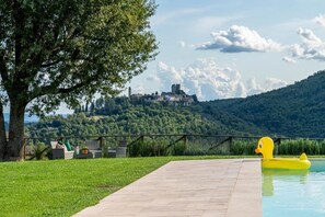 Surrounded by lush greenery, this property offers a serene outdoor setting with a clear view of a historic castle and a swimming pool.