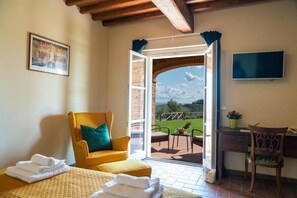 Relax in a cozy seating area with a comfortable armchair and desk near a window opening to a patio with a scenic view.