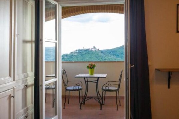 Enjoy a peaceful view of the surrounding hill from this balcony with a table and two chairs.