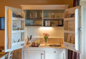 Enjoy cooking in this kitchen with a sink and open shelving for storage.