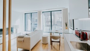 A modern living room with a sofa, ottoman, and a glass dining table. - VIVA Formosa Lofts 1 (Porto)