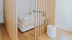 A modern bedroom with a bed, a bedside table, and a wooden partition.