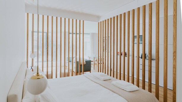 Une chambre moderne avec un grand lit, une lampe de chevet et une vue sur un balcon.
