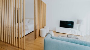 Une pièce moderne et minimaliste, avec un canapé blanc, un téléviseur et une cloison en bois.