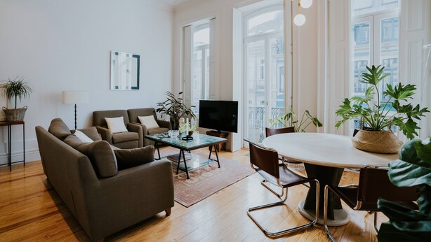 Ein modernes Wohnzimmer mit Sofa, Couchtisch, Fernseher und einem Essbereich mit Stühlen und Tisch.