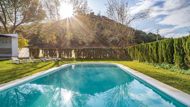 Una piscina con vista despejada del paisaje circundante, incluyendo árboles y setos.