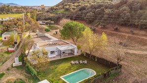 Una casa moderna con piscina, rodeada de un jardín exuberante y un paisaje montañoso.