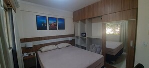 Ein Schlafzimmer mit Bett, Nachttisch, Kleiderschrank und Fenster.