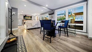 A modern living room with a dining area, large windows, and a view of the outdoors.