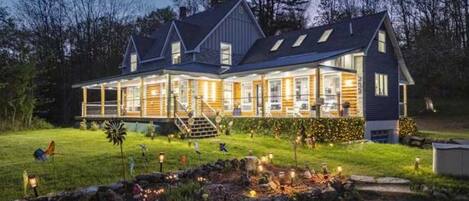 A large, two-story house with a covered porch and a stone garden feature.