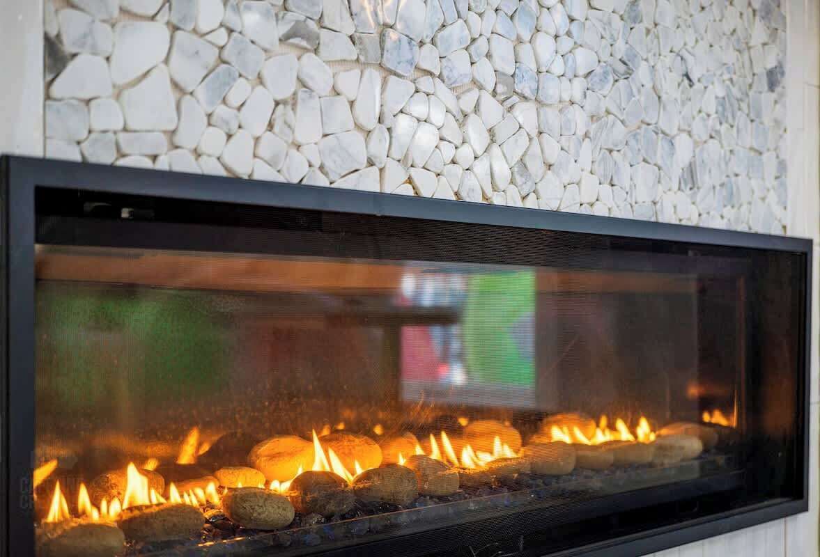 A fireplace with a stone wall backdrop.
