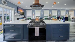 Une cuisine moderne dotée d’un îlot central, de deux fours et de luminaires suspendus.