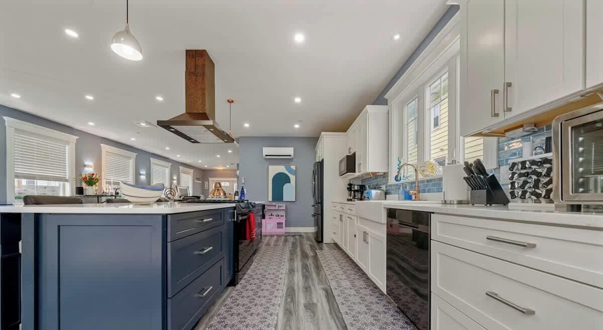 A modern kitchen with white cabinets, a large island, and a hanging light fixture.