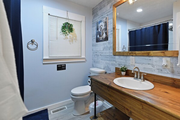 A modern bathroom with a wooden vanity, white sink, and a large mirror. - Spacious Country Setting-Hocking Hills- Hot Tub- Fire Pit- Pool Table (Lancaster)