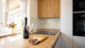 A kitchen with wooden cabinets, a countertop, a bottle of Freixenet champagne, two glasses, a candelabra, and a charcuterie board with meats and cheese. - Stunning home in Sinj (Sinj)