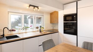 A modern kitchen with a window, sink, countertop, wooden cabinets, and a Bosch oven. - Stunning home in Sinj (Sinj)