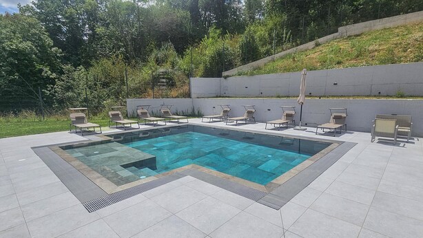 A rectangular outdoor swimming pool with a tiled deck and multiple lounge chairs arranged around it. - Stunning home in Sinj (Sinj)