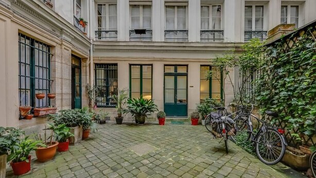 A courtyard with a cobblestone floor, potted plants, and a bicycle. - Manu apartment   Paris (Paris)