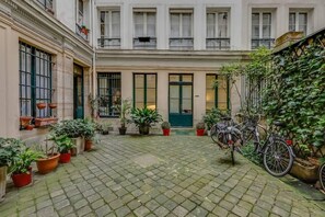 A courtyard with a cobblestone floor, potted plants, and a bicycle. - Manu apartment   Paris (Paris)