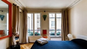 A hotel room with a large bed, a mirror, a window with curtains, and a view of the outside. - Manu apartment   Paris (Paris)