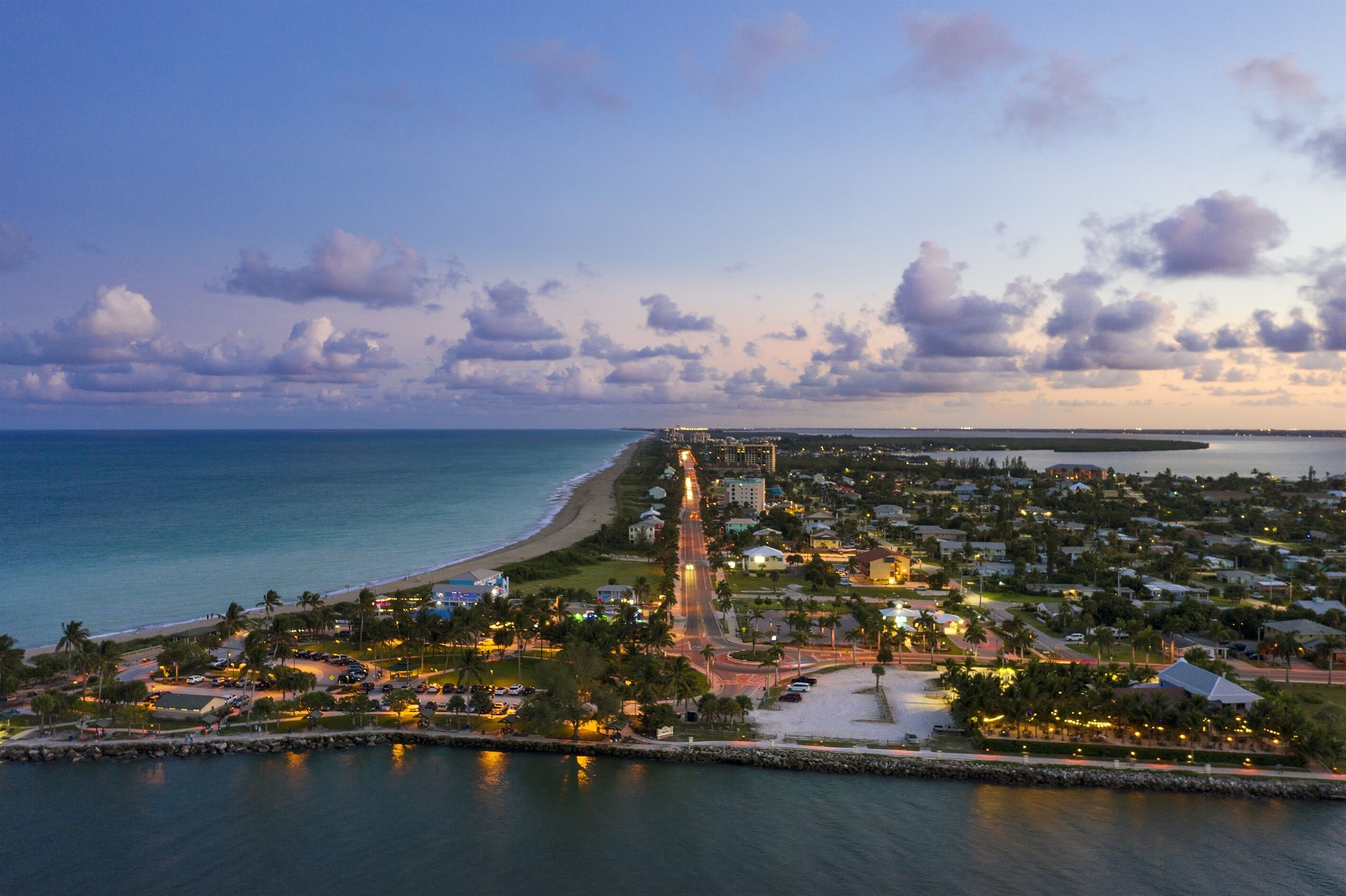 An aerial view of a coastal town with a beach, roads, and buildings.
