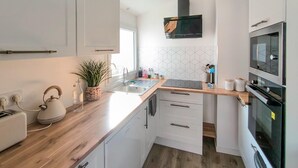 A modern kitchen with white cabinets, a wooden countertop, a built-in microwave, and a stainless steel sink. - 2 bedroom stunning home in L'Aiguillon la Presqu' (L'Aiguillon la Presqu')