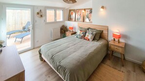 A bedroom with a large bed, two bedside tables with lamps, a radiator, and a view of an outdoor patio. - 2 bedroom stunning home in L'Aiguillon la Presqu' (L'Aiguillon la Presqu')