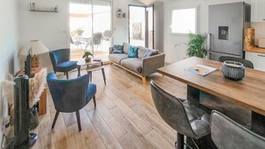 A modern living room with a sofa, chairs, a coffee table, and a dining area with a table and chairs. - 2 bedroom stunning home in L'Aiguillon la Presqu' (L'Aiguillon la Presqu')