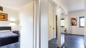 Un dormitorio moderno con cama, mesita de noche y un espejo grande.