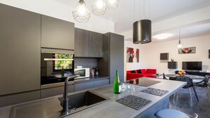 Una cocina moderna con una isla central, electrodomésticos de acero inoxidable y un sofá rojo en la sala de estar.