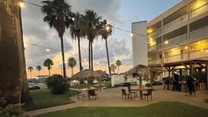 An outdoor area with palm trees, string lights, and a building with balconies.