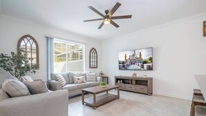 Ein Wohnzimmer mit Sofa, Couchtisch, Fernseher und Deckenventilator.
