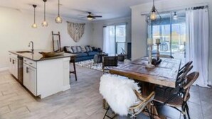 A modern kitchen with a central island, dining area with chairs, and a ceiling fan. - Go!#19 - CHAMPIONS GATE (Kissimmee)