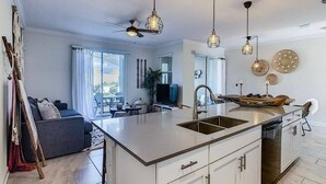 A modern kitchen with a central island, pendant lighting, and a dining area with a view. - Go!#19 - CHAMPIONS GATE (Kissimmee)
