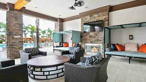 An outdoor lounge area with wicker furniture, a round table, and a stone fireplace.