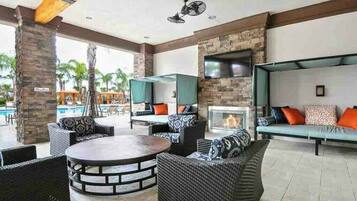 An outdoor lounge area with wicker furniture, a round table, and a stone fireplace.