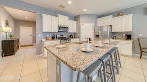 A modern kitchen with white cabinets, granite countertops, and a central island with bar stools.