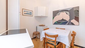 Un comedor con una mesa preparada para cuatro, un refrigerador pequeño y un cuadro en la pared.
