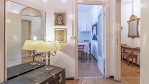 Un pasillo con una lámpara, un espejo y una puerta que da a un comedor.
