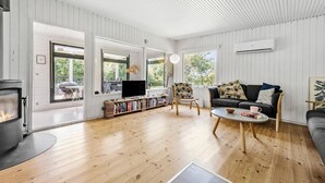 Een ruime woonkamer met een open haard, een zithoek, een salontafel en een boekenkast.