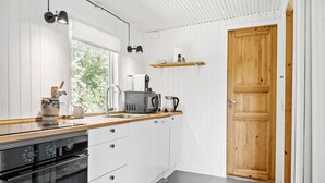 Een moderne keuken met witte kastjes, een houten aanrecht, een ingebouwde oven en een houten deur.