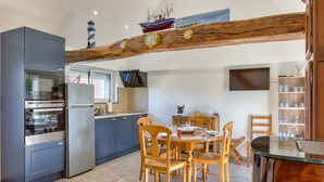 Une cuisine équipée d’appareils électroménagers modernes, un coin repas avec des chaises en bois et une poutre en bois rustique au-dessus de la table.