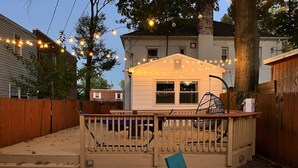 A backyard with a wooden deck, a swing chair, and a small table. - Luxurious 3-Level Home Minutes from Washington D.C. (Arlington)
